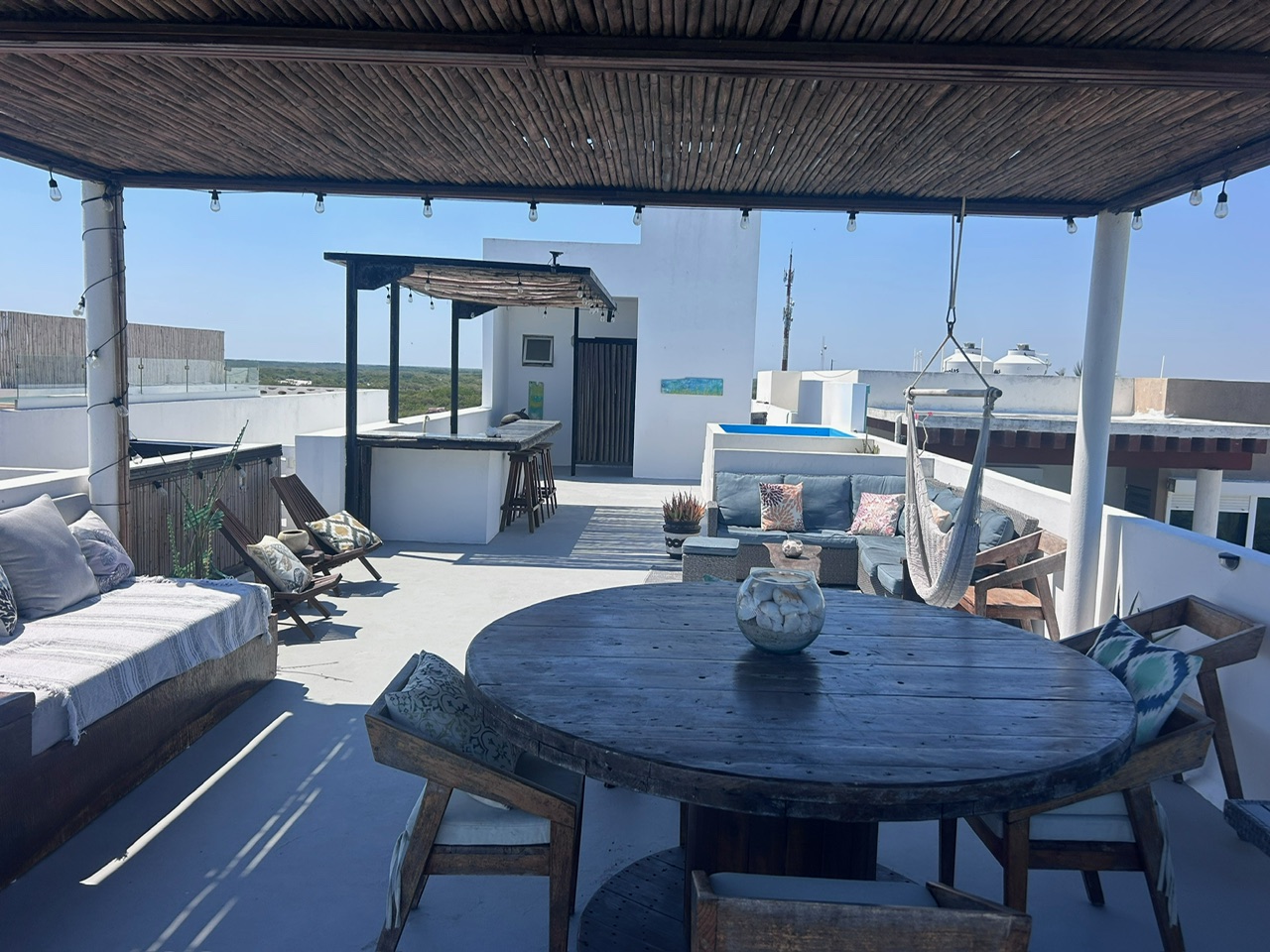 Covered rooftop lounge with dining table and hammock